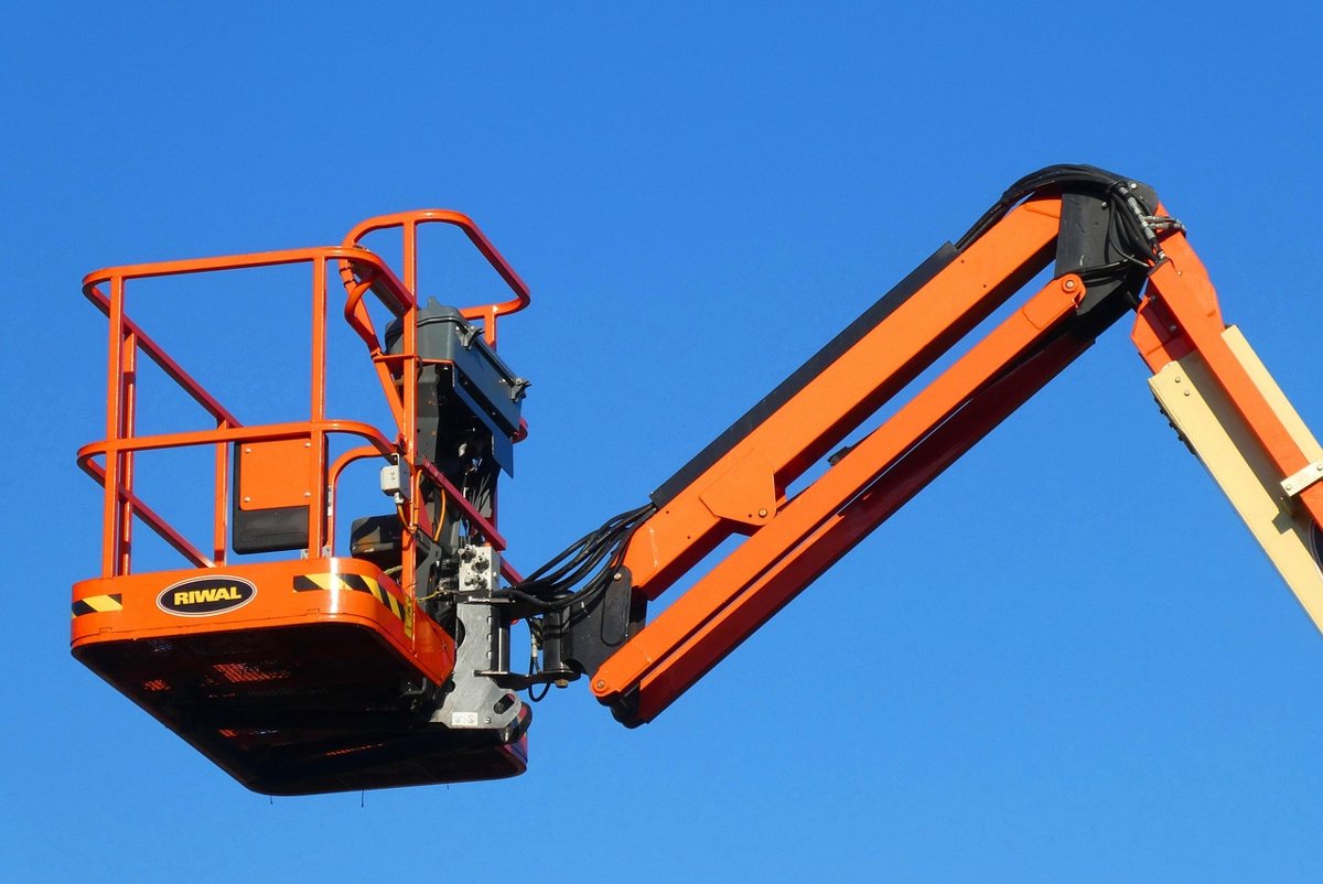 Orange articulating boom lift basket raised against a clear blue sky